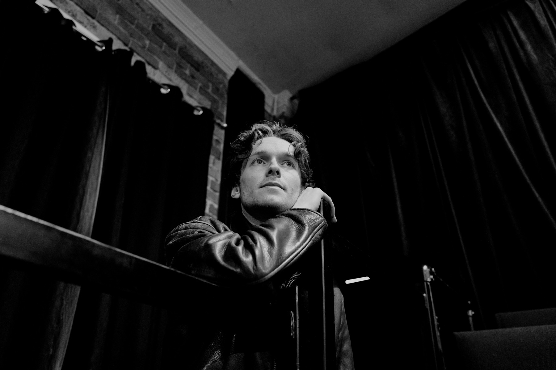Hamlet performer seated near a stage curtain