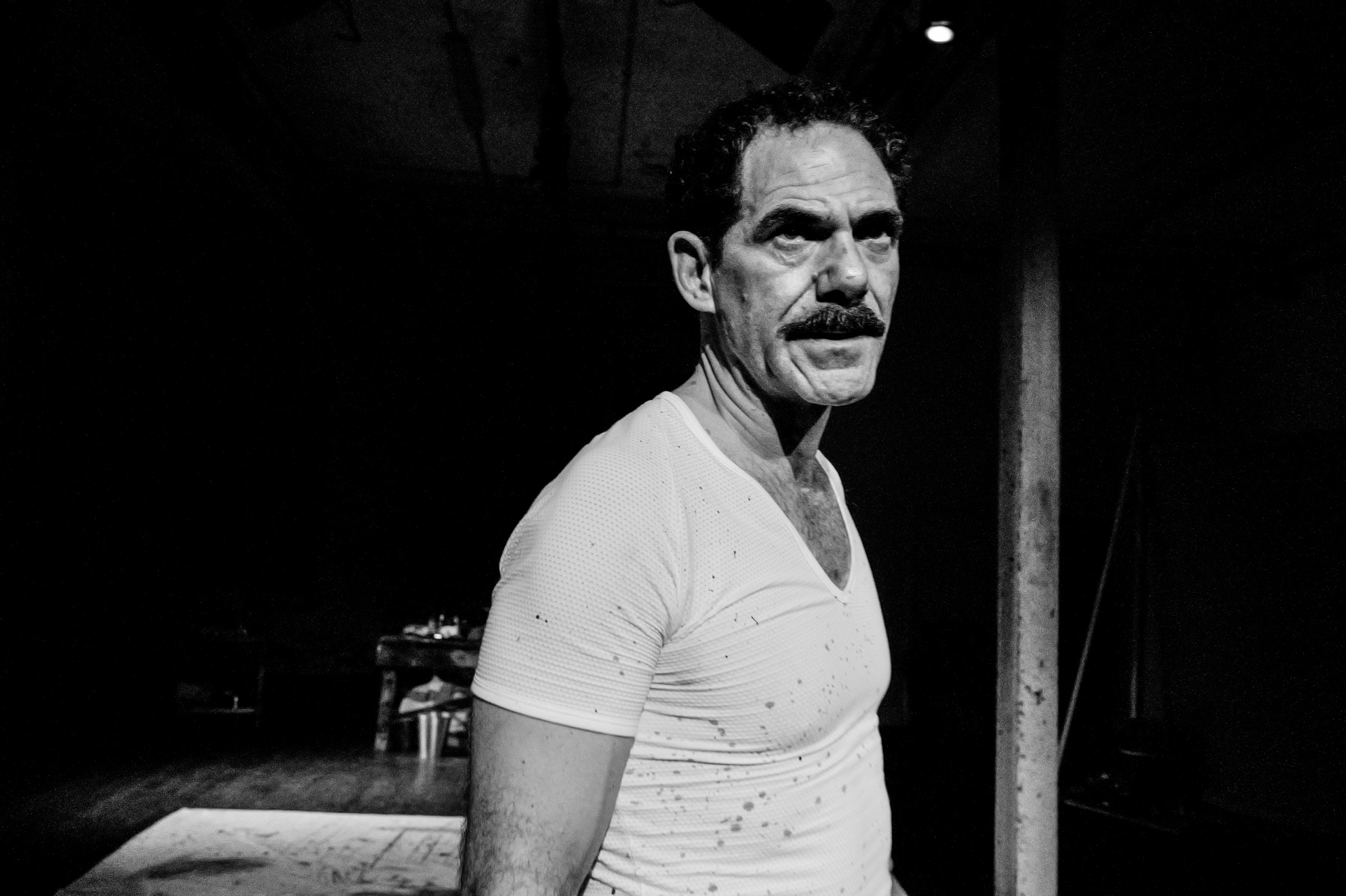 Red production photograph of a performer under stage light